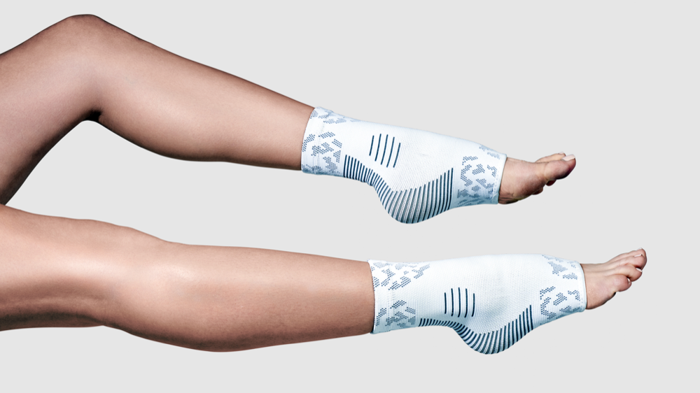 A pair of white NanoSocks worn on both legs and photographed side-on against a plain studio background, with the bare toes coming out through the open toe box at the end of each sock.